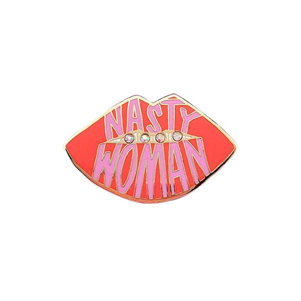 By Little Arrow. Nasty Woman Pin: Cloisonné enamel set in 22kt plated gold with 4 iridescent rhinestones. Rubber clasp. Measures 1.5 x 1.25 inches. Also available in store at FOLD Gallery DTLA.